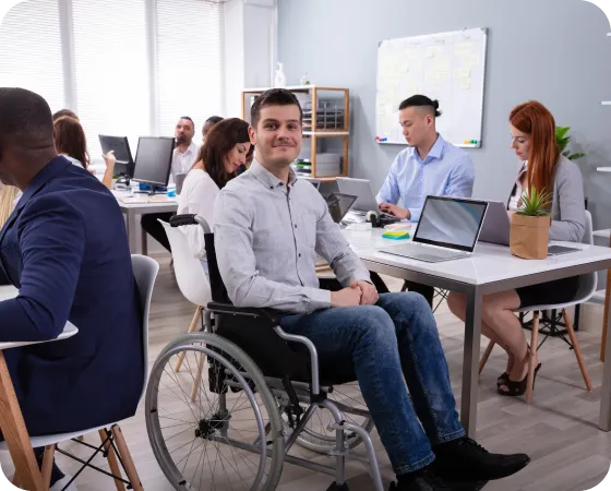 A person in a wheelchair in a room with people around him